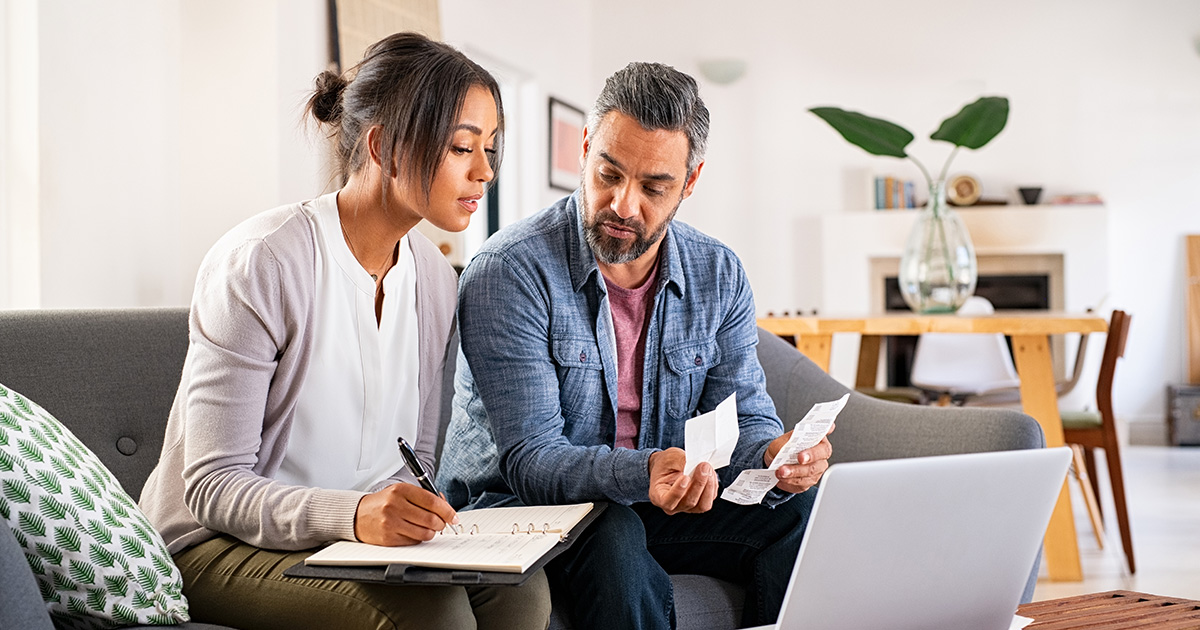 Mature couple calculating bills at home using laptop