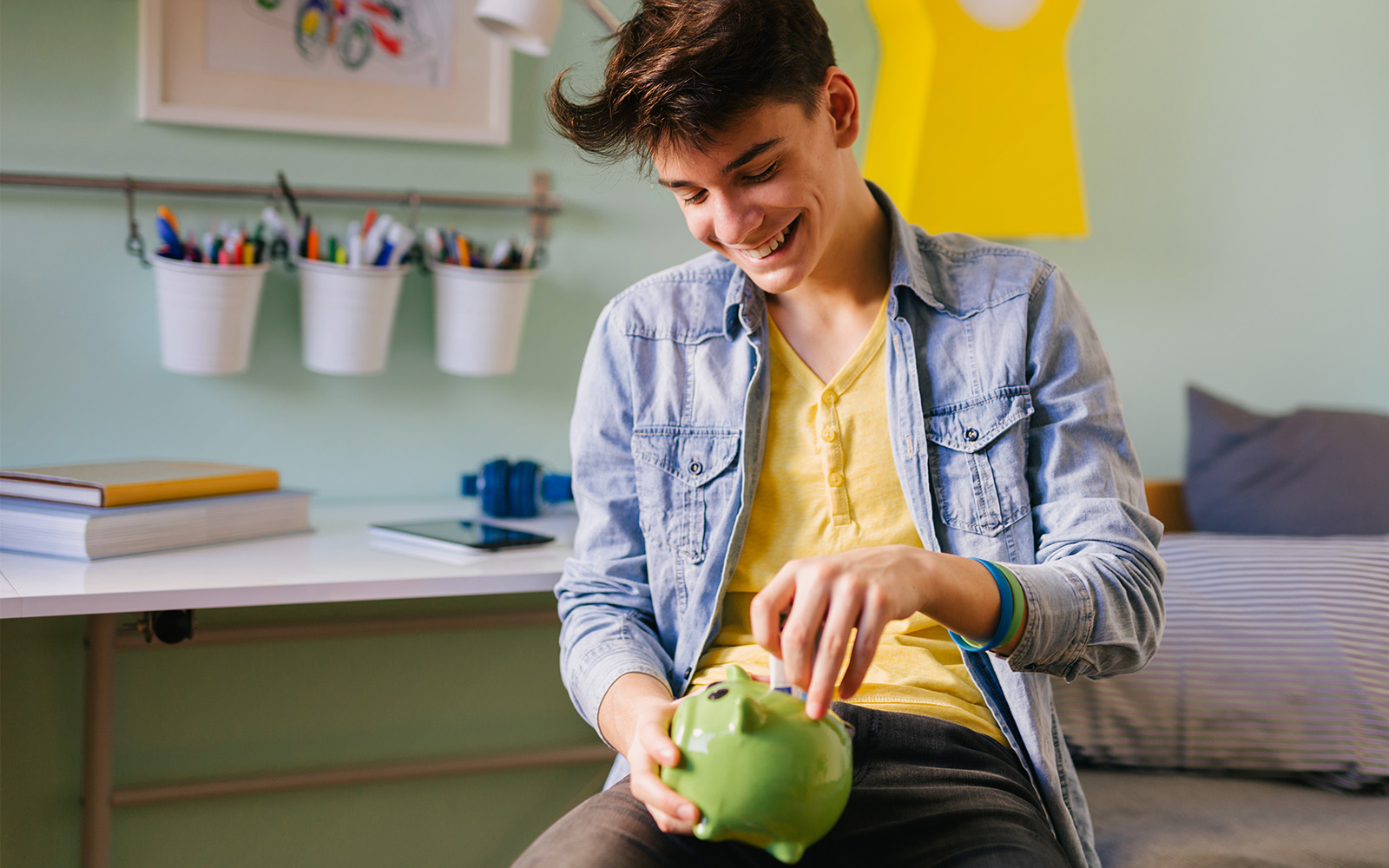 Teenage boy holding piggy bank