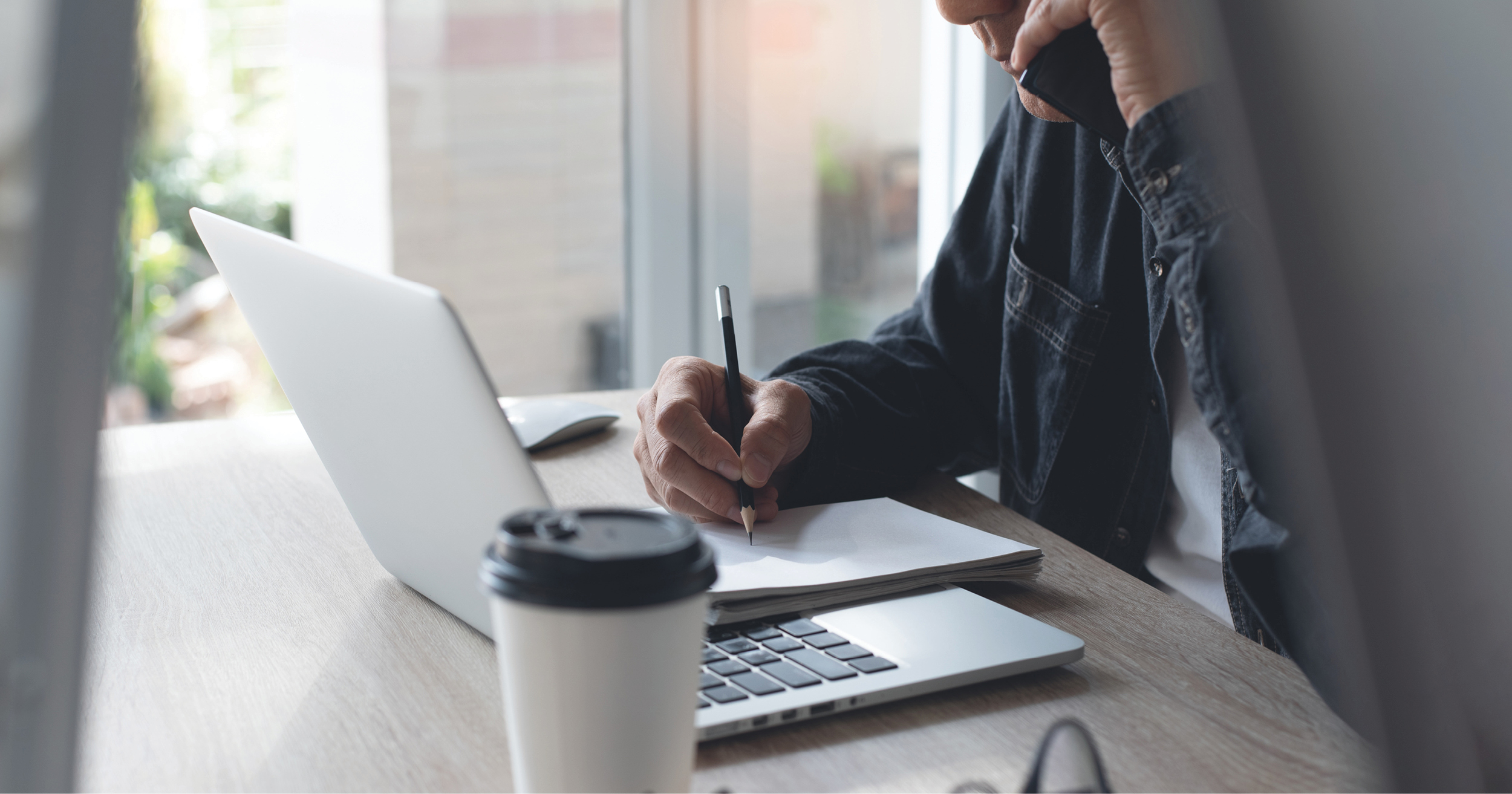 man working at home beside a laptop and a note pad