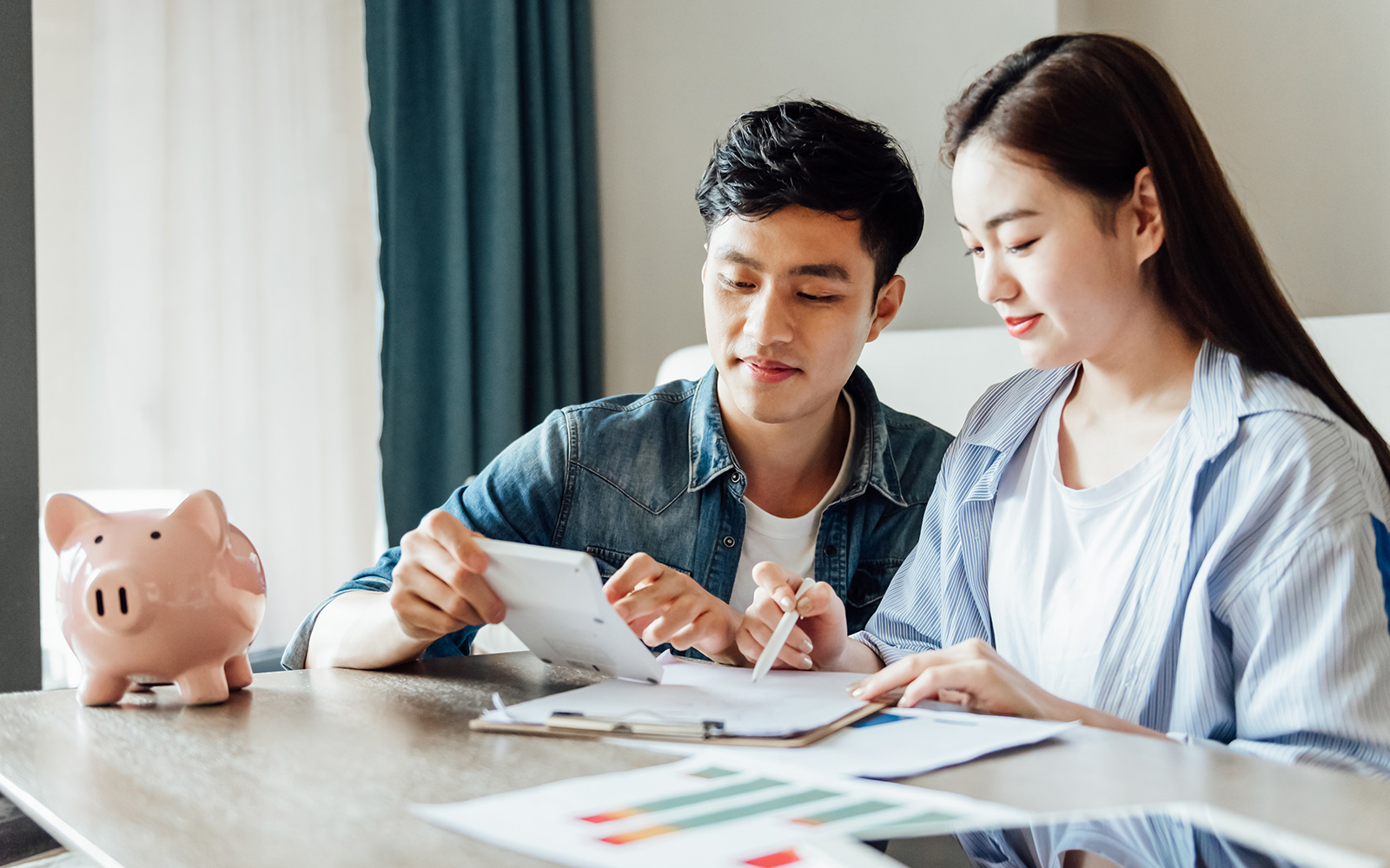 Image of a couple sitting at a table looking at a calculator and papers