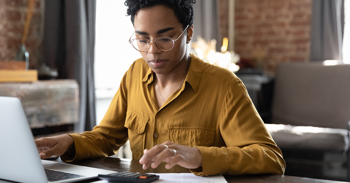 Woman calculating finance using calculator laptop computer