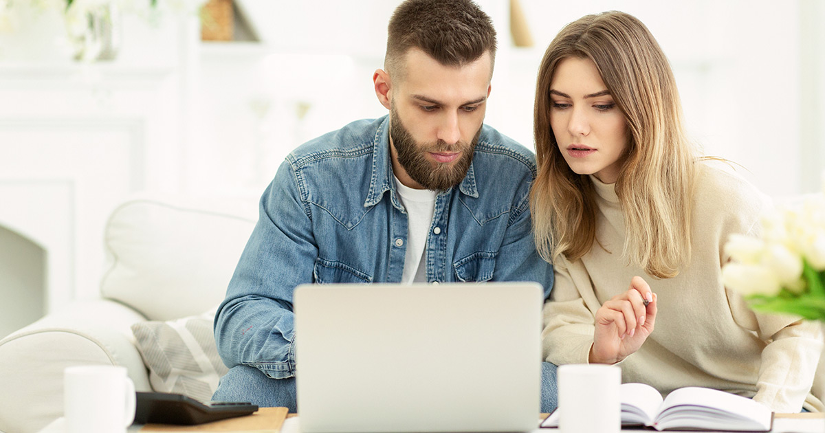 Married couple managing expenses with laptop and checking accountancy and bills