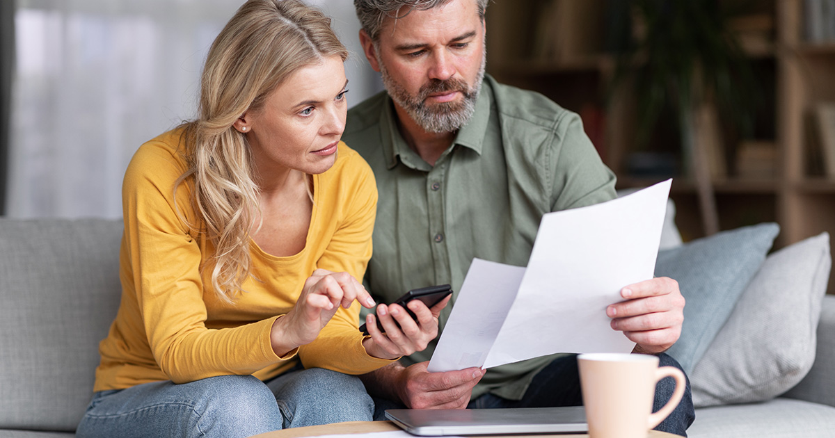 Couple Planning Budget Together Reading Papers And Calculating Spends.