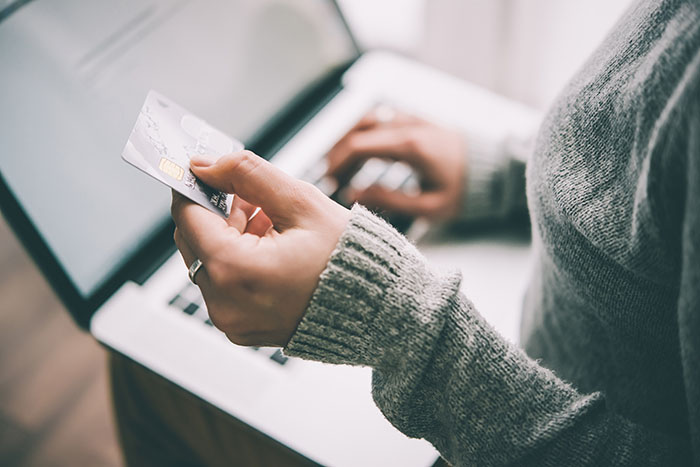 Person online shopping on their laptop holding a credit card