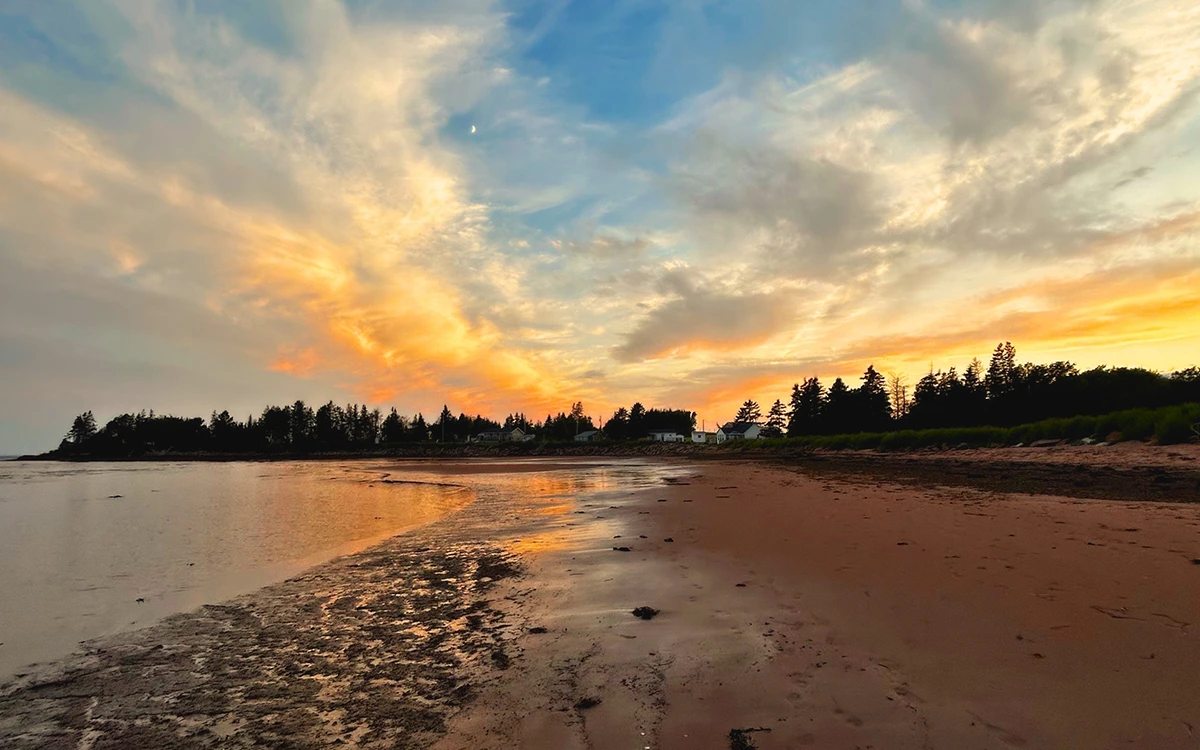 Sunset over a beach with water running off the beach