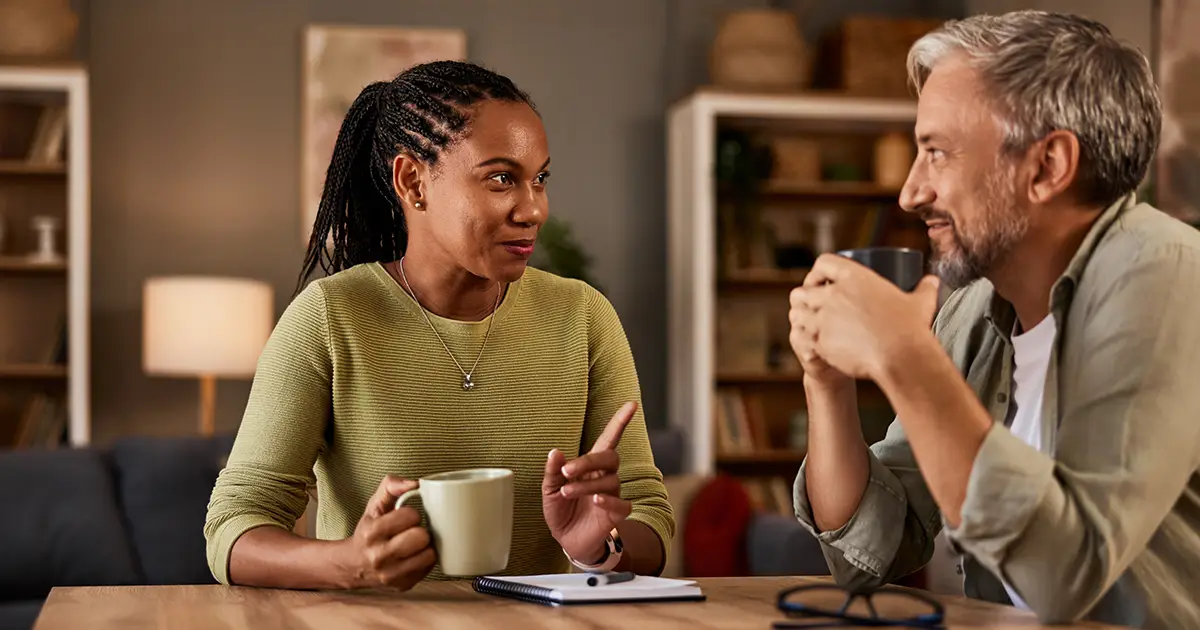 Two individuals are deep in conversation while enjoying a comforting drink at their home table