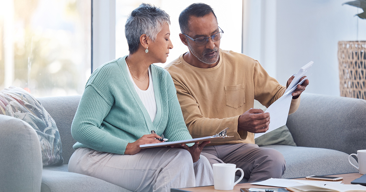 Couple sitting on couch reviewing documents