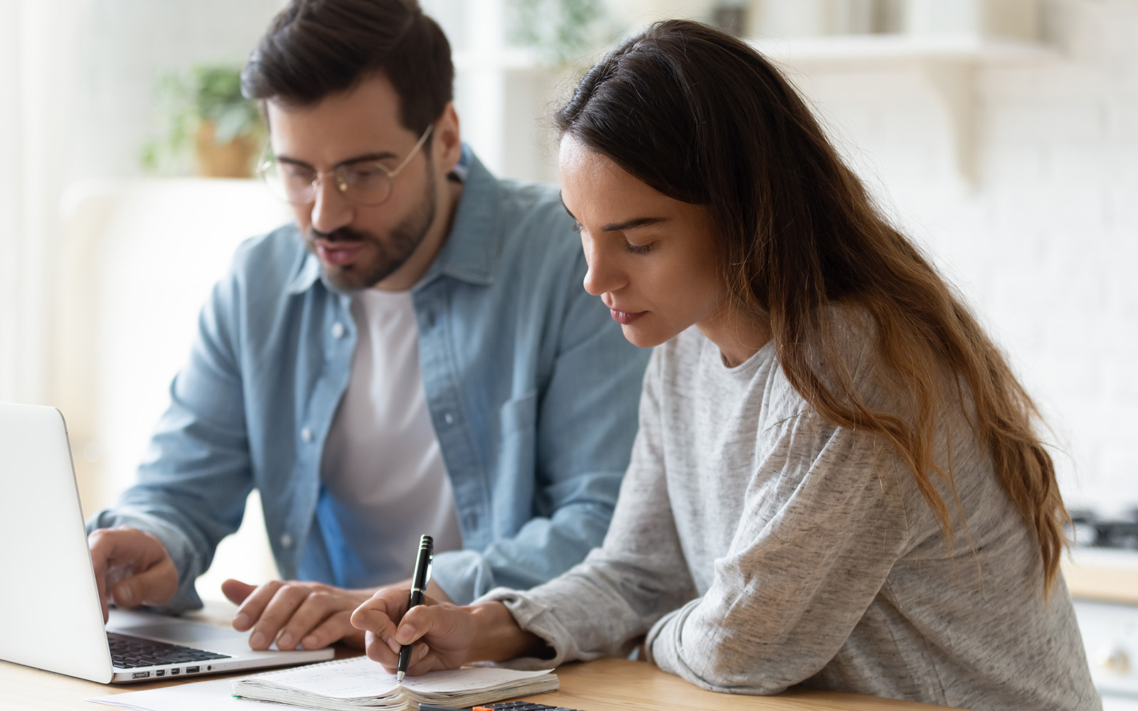 Woman writing on notepad and man on laptop