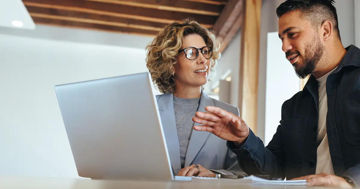 two people meeting and reviewing information on a laptop together