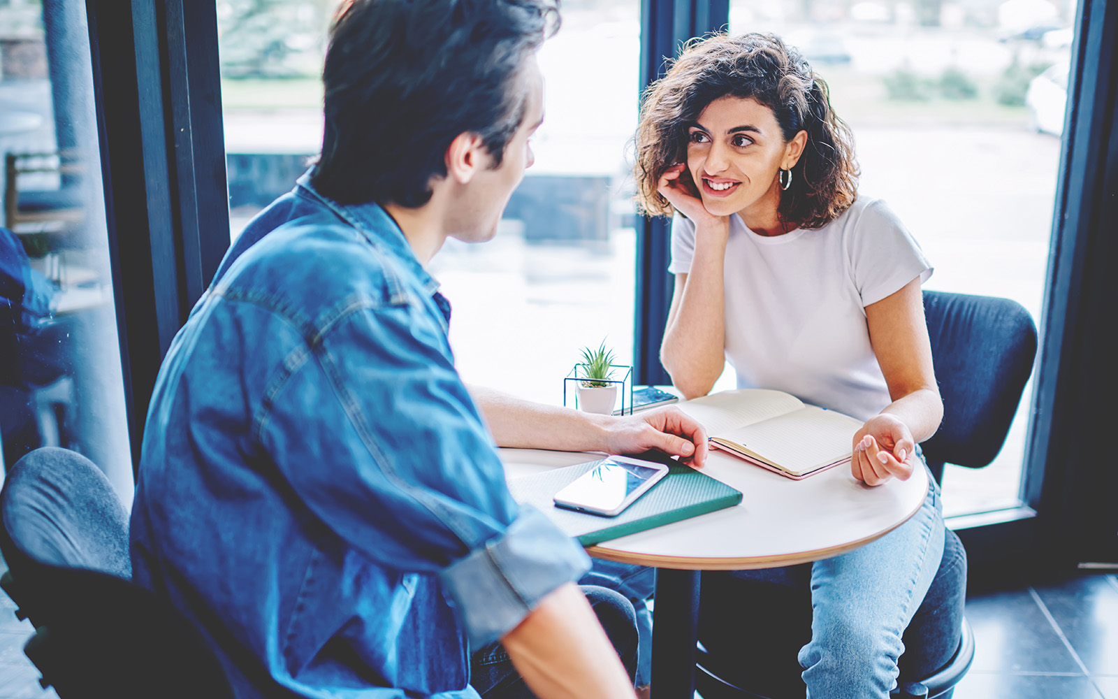 Meeting of two friends at coffee table in cafeteria