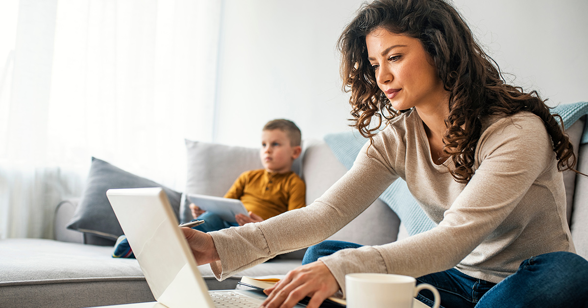 Woman on a laptop while sitting on a couch.