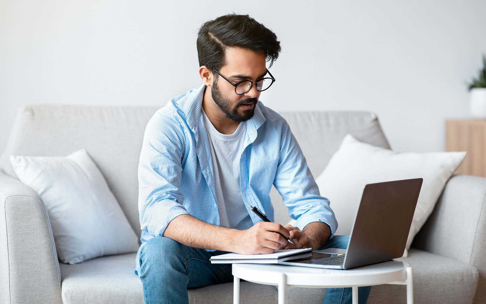 Man sitting on couch looking at laptop on table in front of him