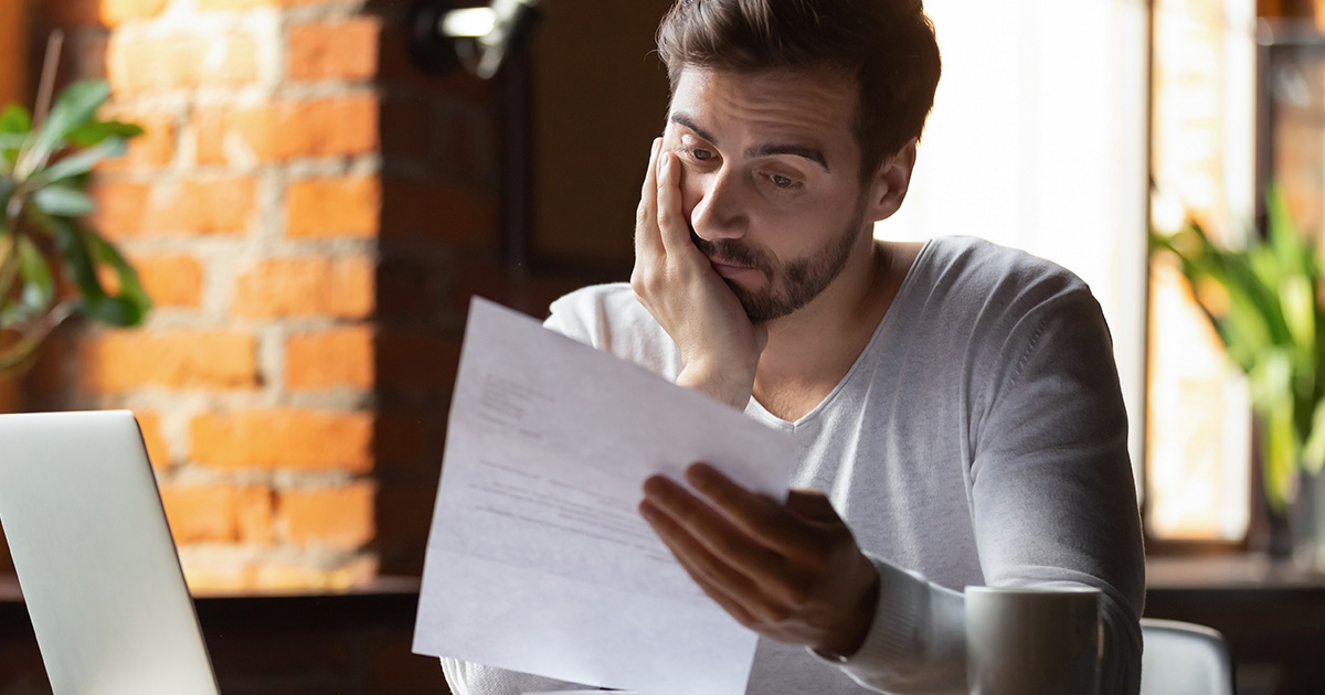 A young man reading a letter in a cafe.