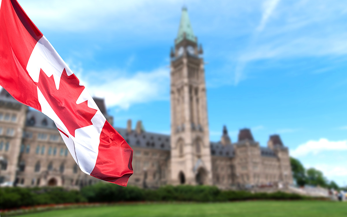 Canadian flag with the Canadian Parliament building in the background.