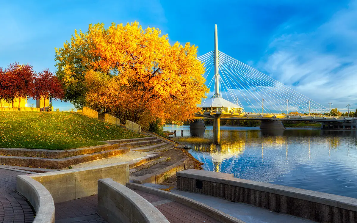 A scenic view of a river and bridge surrounded by autumn trees