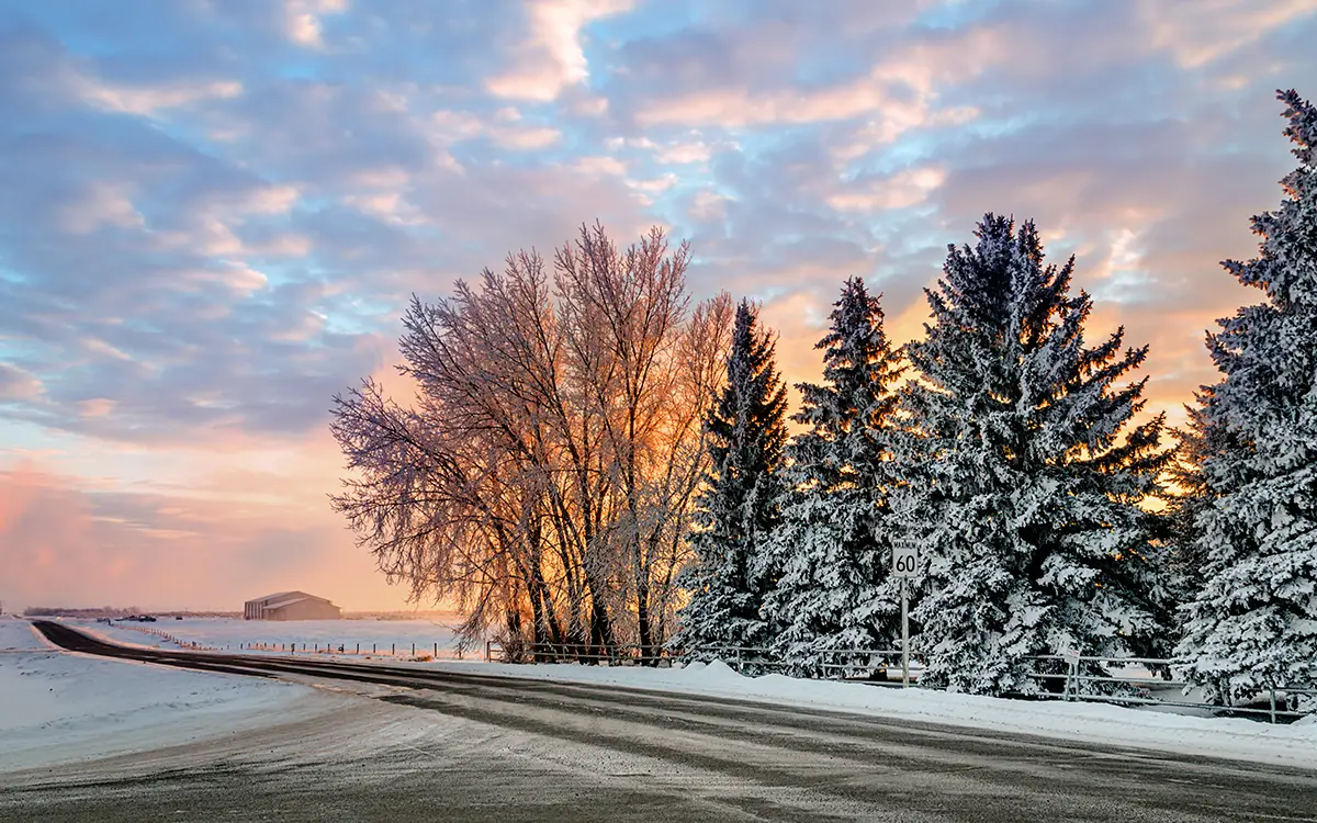 Sun setting over empty prairie road with snow on them