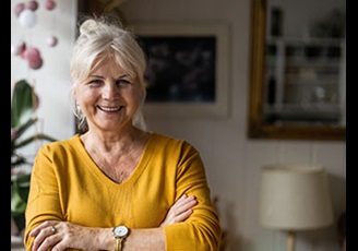 mature woman wearing a yellow sweater smiling.