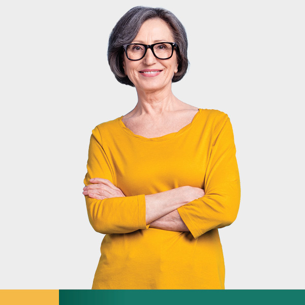 Older woman in yellow shirt smiling with arms crossed