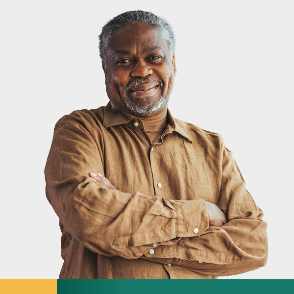 Middle aged man in brown shirt smiling with arms crossed